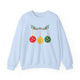 Light blue crewneck sweatshirt with pickleballs styled as Christmas ornaments hanging from a holly branch