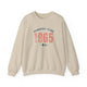 Sand pickleball crewneck sweatshirt with a distressed collegiate-style "Bainbridge Island 1965 WA" text stack in navy and coral